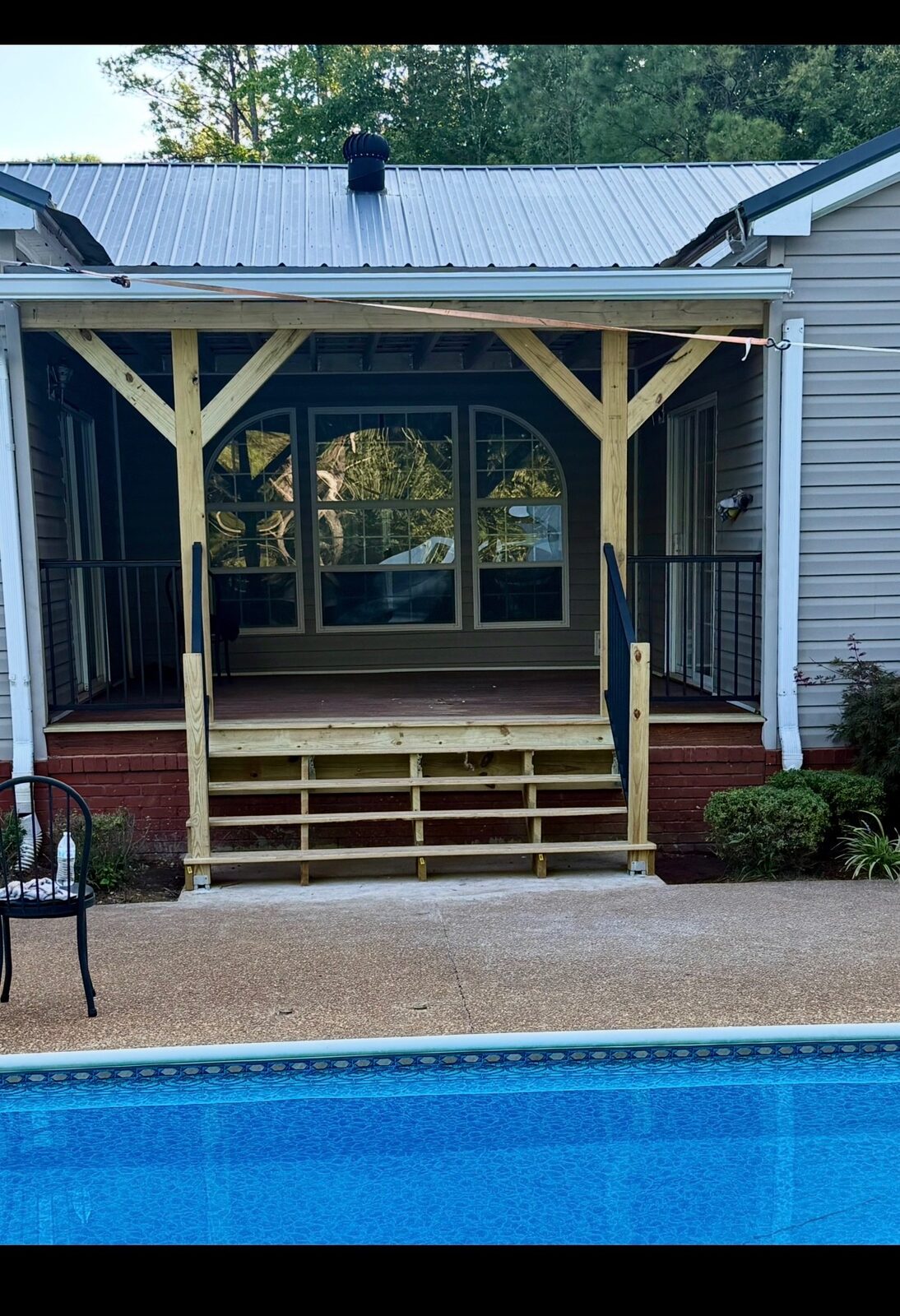 After: finished covered porch with new stairs and metal railings beside the pool
